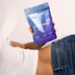 Una persona tiene in mano un pacchetto blu con la scrittaShape Well" mentre indossa i jeans.