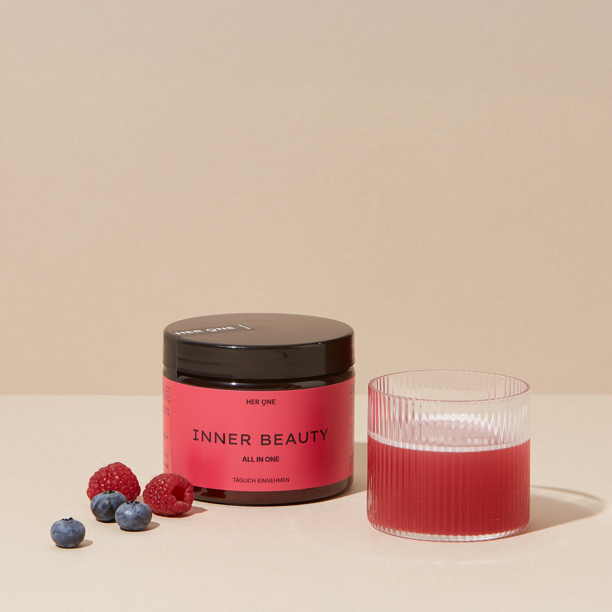 Barattolo rosso scuro HER ONE INNER BEAUTY bacche e succo mescolato in un bicchiere.