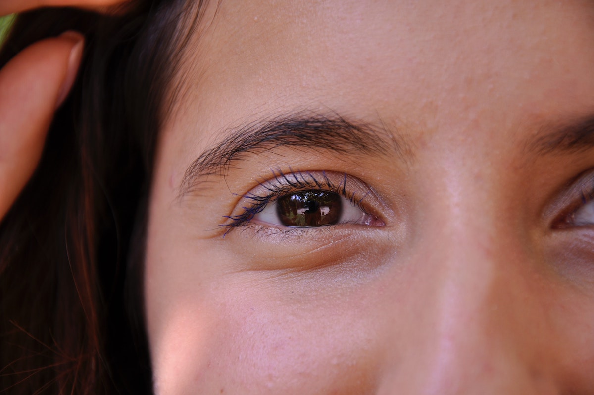 Close-up van een bruin oog met expressieve wimpers en wenkbrauwen.