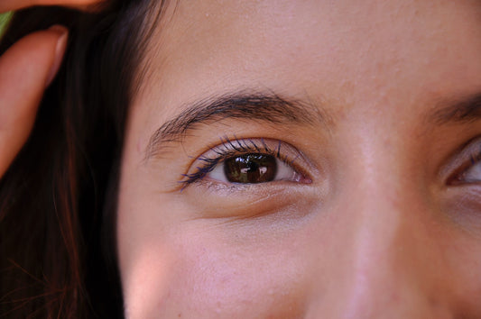 Close-up van een bruin oog met expressieve wimpers en wenkbrauwen.