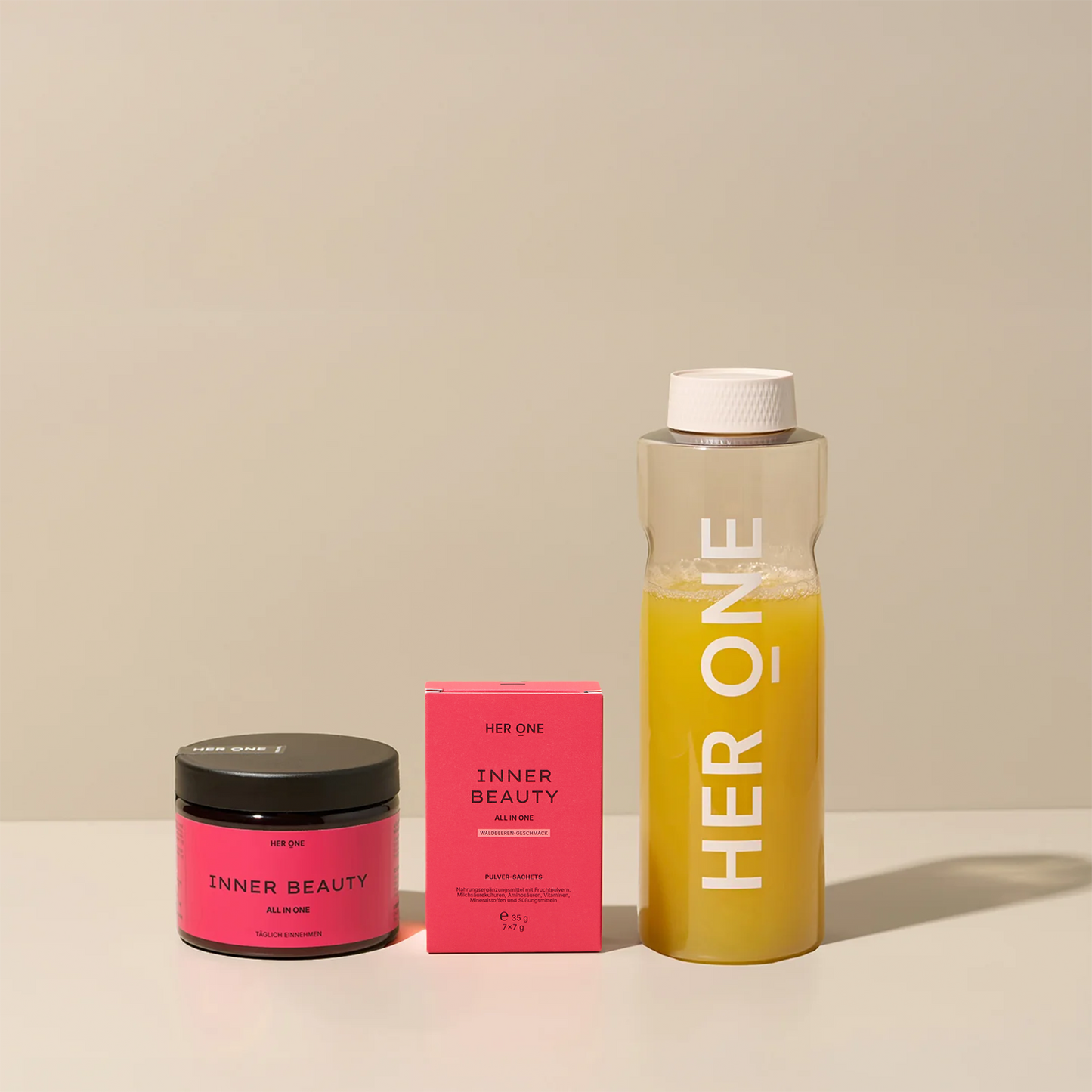 HER ONE Inner Beauty Startset: blikje, doosje en shaker met gele drank, gerangschikt op een lichtgekleurde achtergrond