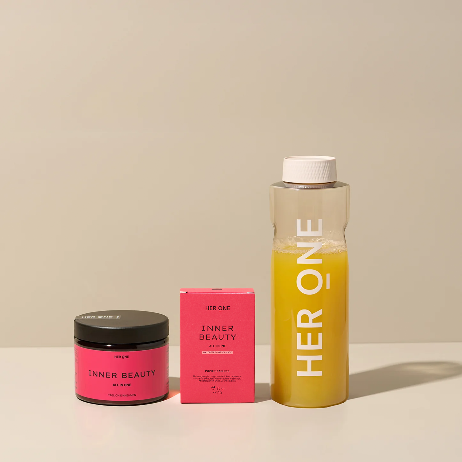 HER ONE Inner Beauty Startset: blikje, doosje en shaker met gele drank, gerangschikt op een lichtgekleurde achtergrond