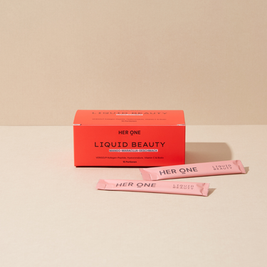 HER ONE Liquid Beauty Box en twee roze sticks tegen een beige achtergrond
