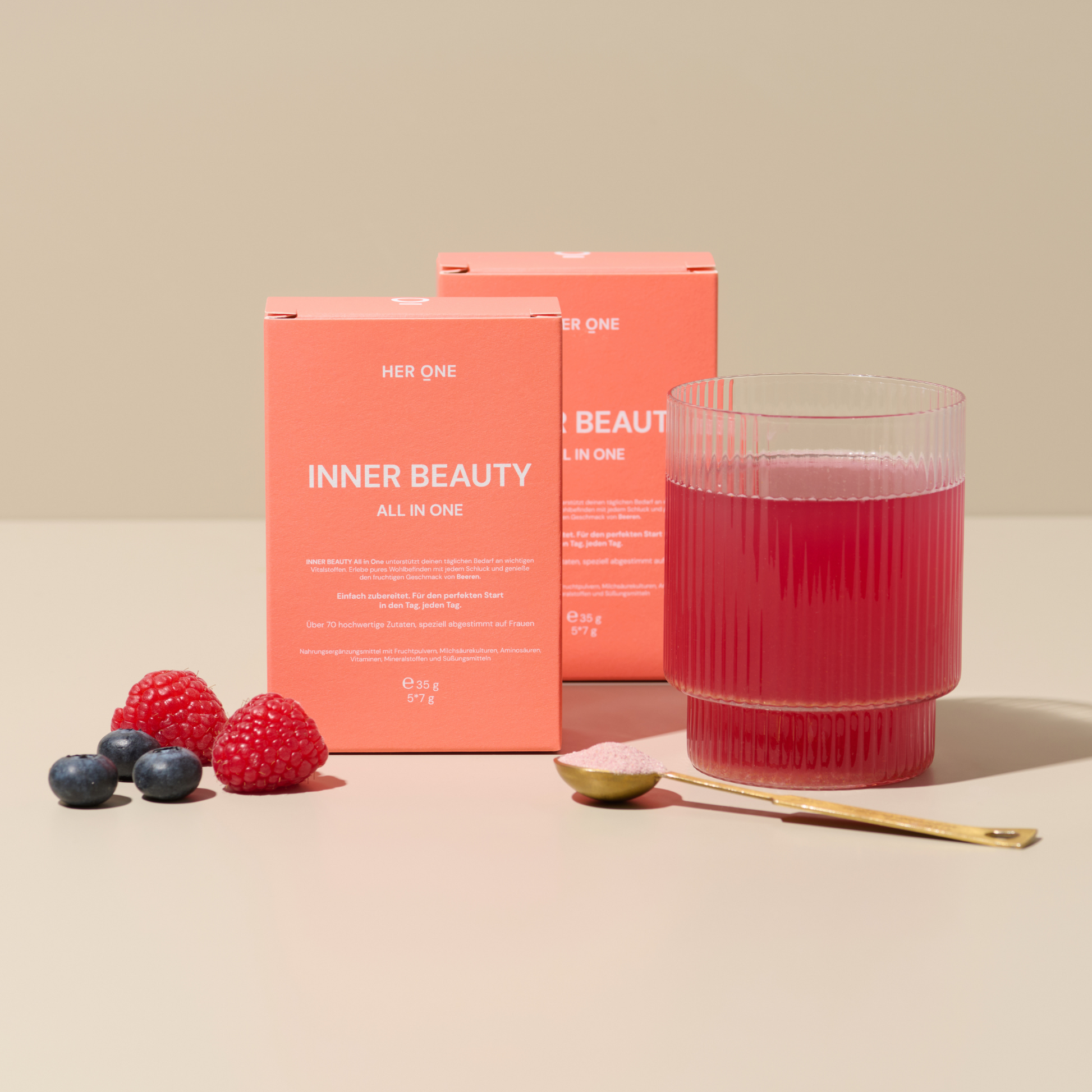 Rode verpakking vanINNER BEAUTY" naast een glas rode drank, bessen en een lepel met poeder.